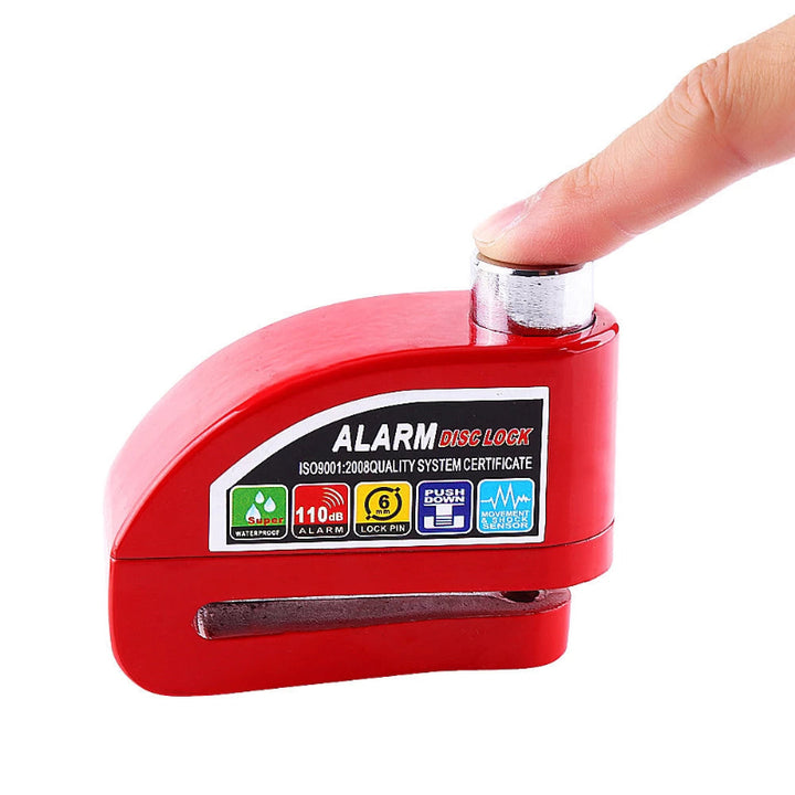 Finger pressing down to arm the Red Disc Brake Lock Alarm