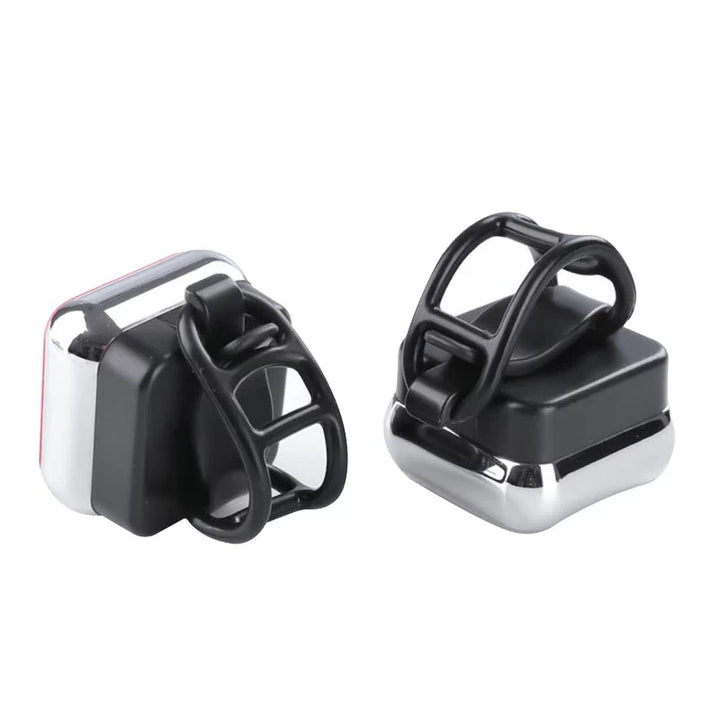 Two compact waterproof red rear safety lights with black silicone attachment rings, designed for easy installation on bicycles, helmets, or backpacks.
