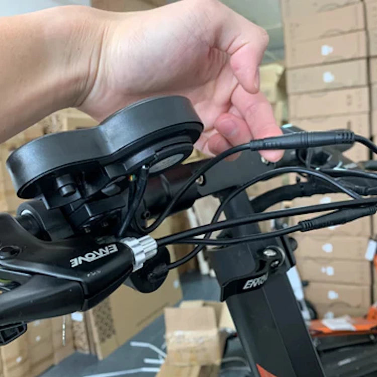 Close-up of a user installing the horizontal thumb throttle on the handlebar of an EMOVE Touring electric scooter, highlighting the simplicity of the plug-and-play setup.