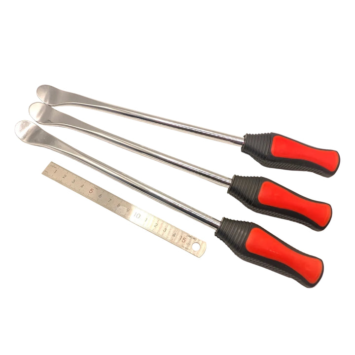 Three metal tyre levers beside a metric ruler, showing curved spoon tips and red and black handles