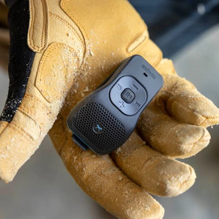 Durable NoxGear 39g Bluetooth speaker placed on a gloved hand, highlighting its rugged design for job site use.