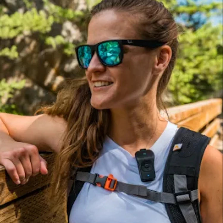 Woman hiking outdoors with the NoxGear 39g Bluetooth speaker clipped to her T-Shirt.