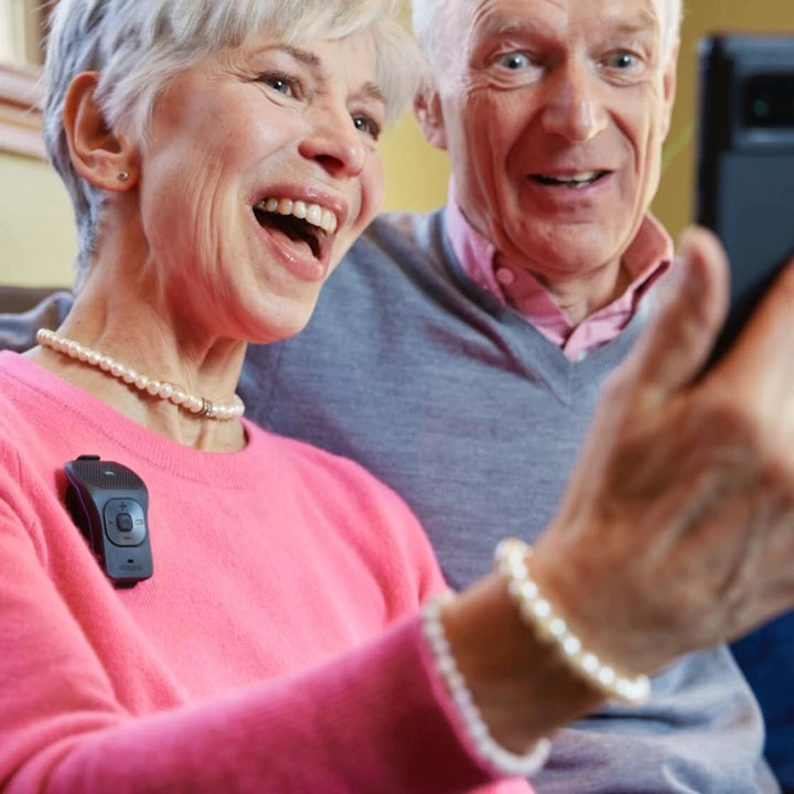 Couple enjoying a video call with the NoxGear 39g Bluetooth speaker clipped to their top for clear audio.