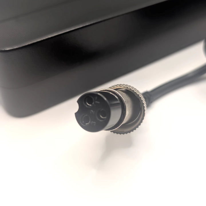 Close-up of the GX16-3 female charging connector showing three sockets and threaded locking collar.