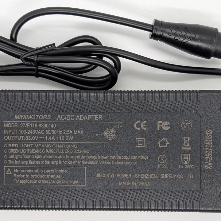 Close-up view of the Minimotors XVE118-8300140 charger specifications label showing 83V 1.4A 116.2W output and CE, FCC and Level VI (6) charger certification.
