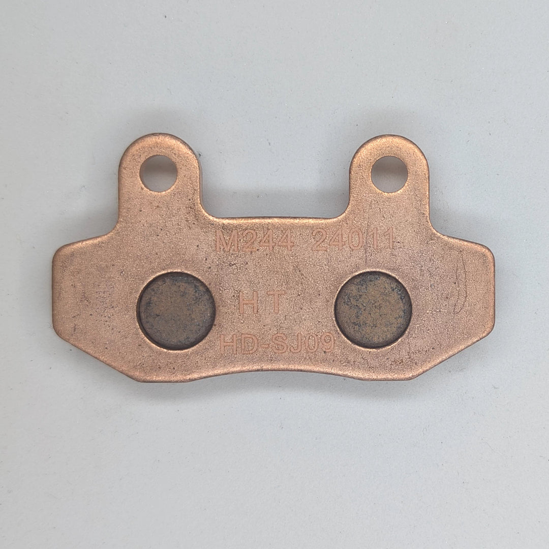 Surron Ultra Bee brake pad backing plate showing M244, HT and HD-SJ09 markings