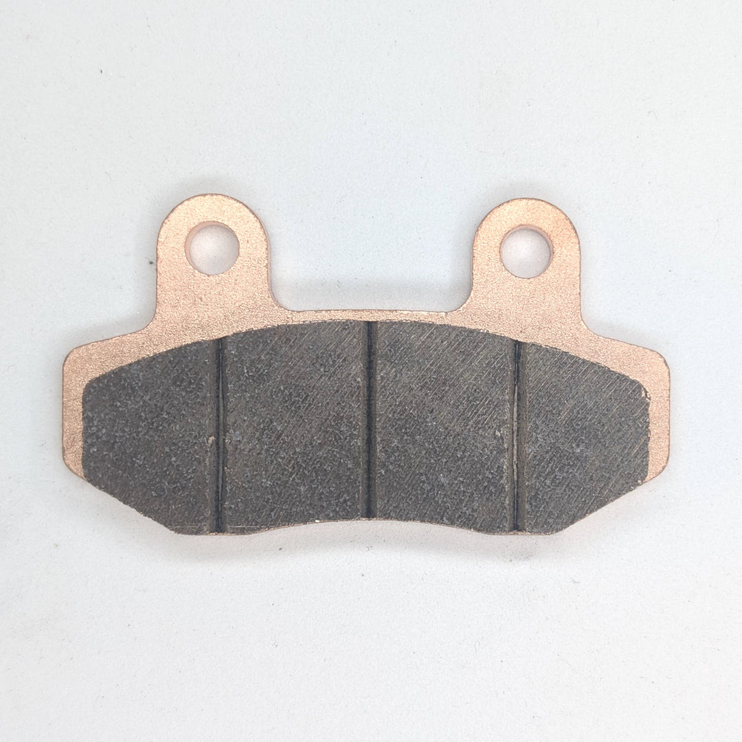 Close-up of Surron Ultra Bee sintered brake pad friction material with three grooves and two mounting holes