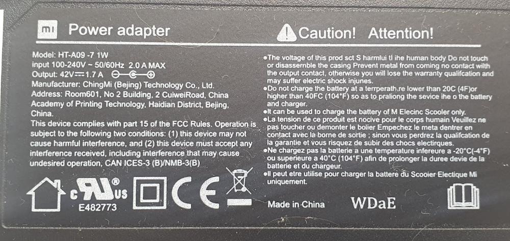 Close-up label on Mi/Xiaomi 42V 1.7A power adapter, showing input/output details, technical data and manufacturer information, as well as safety warnings.