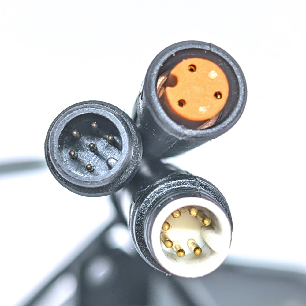 Close-up view of the three Julet connector plugs on the Bexly Raven M9 Hex Diamond Display. One white 7-pin (male), an orange 3-pin (female) and a black 6-pin (male) plug