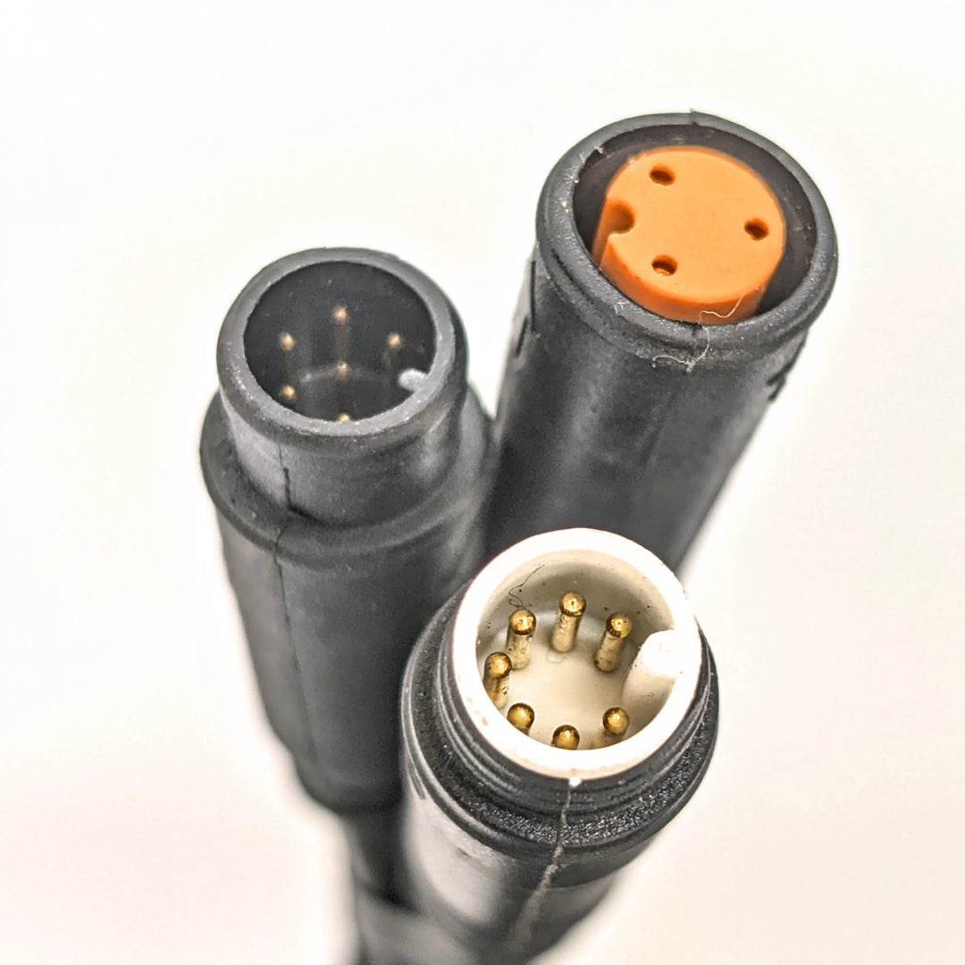Close-up view of the three connector plugs, a white 7-pin (male), an orange 3-pin (female) and a black 6-pin (male) on the Bexly Raven M9 Hex Diamond Display.