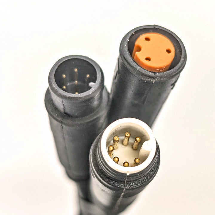 Close-up view of the three connector plugs, a white 7-pin (male), an orange 3-pin (female) and a black 6-pin (male) on the Bexly Raven M9 Hex Diamond Display.