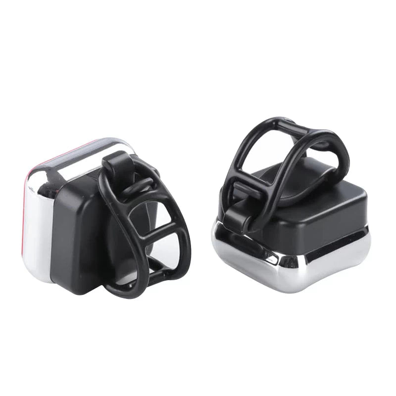 Two compact waterproof red rear safety lights with black silicone attachment rings, designed for easy installation on bicycles, helmets, or backpacks.