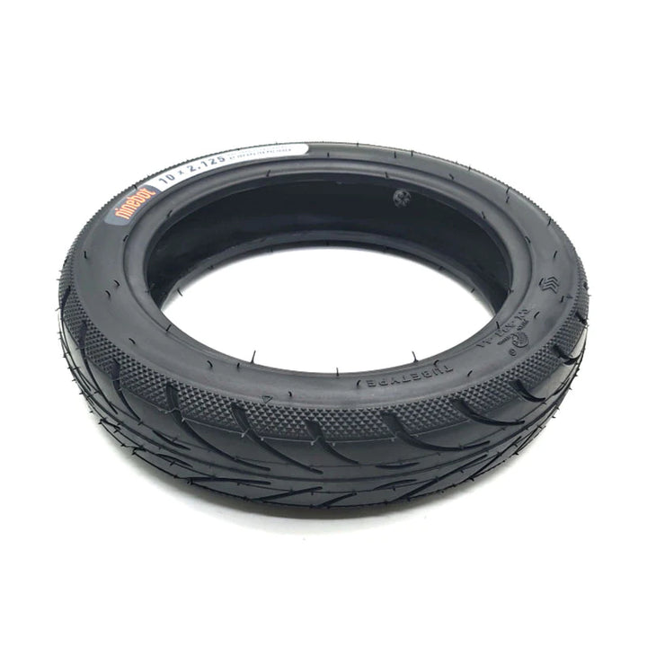 Low angle view of Genuine Ninebot 10x2.125 Tyre, showing directional road tread pattern, with diamond stippled shoulder.