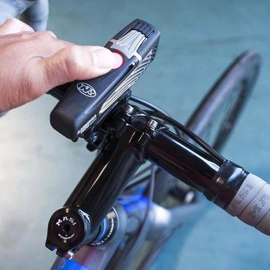 Cyclist easily operating the NiteRider Lumina 1000 Boost headlight while mounted on bicycle handlebars.