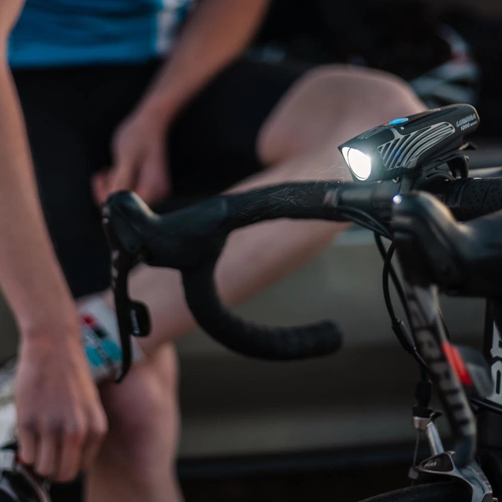 Cyclist using NiteRider Lumina 1200 Boost headlight during daylight, mounted on handlebars for extra visibility.