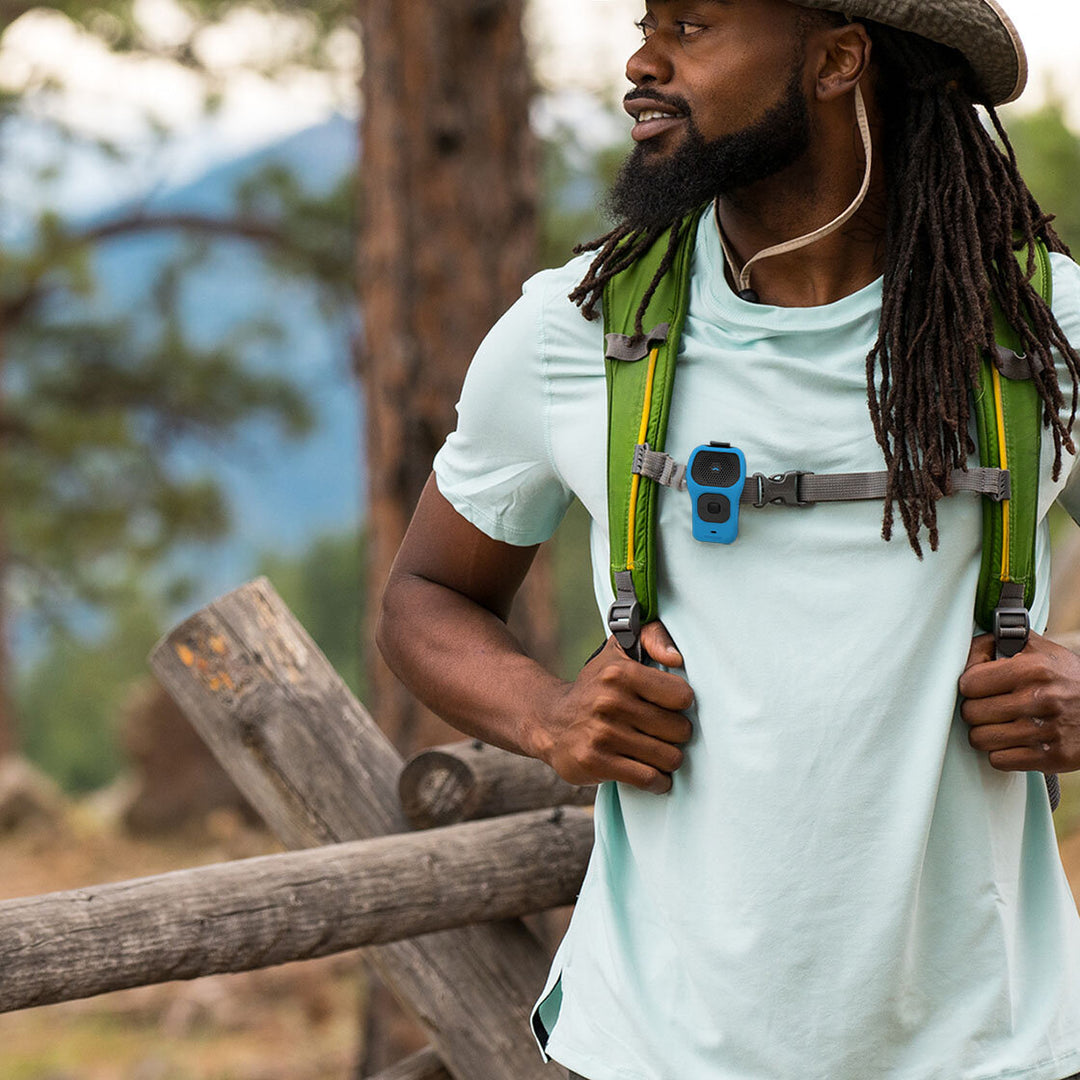 Noxgear 39g Bluetooth speaker with Blue silicone skin clipped to a backpack chest strap during outdoor use.
