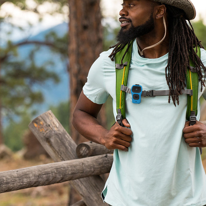 Noxgear 39g Bluetooth speaker with Blue silicone skin clipped to a backpack chest strap during outdoor use.