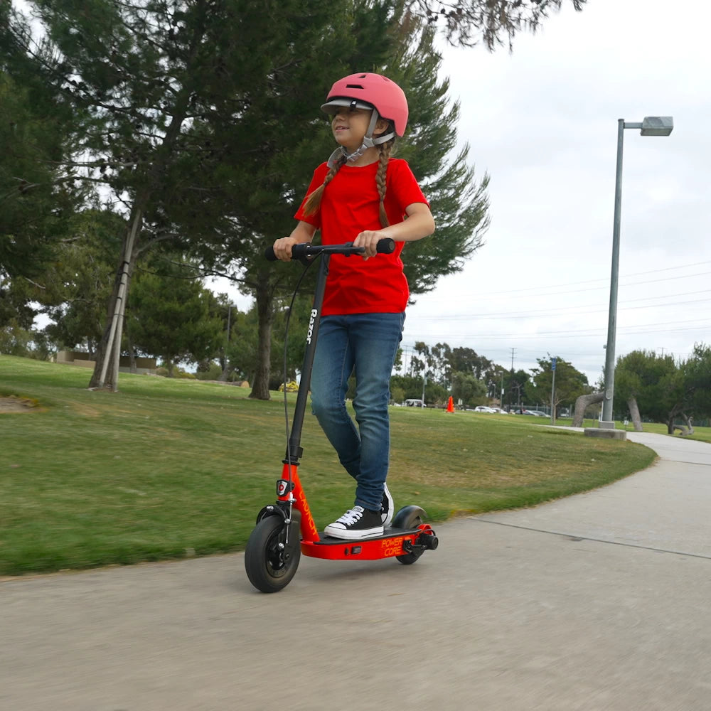 Side view of a child riding the Razor PowerCore Launch electric scooter by a lake, ideal for children aged 8+ years, promoting safe outdoor fun.