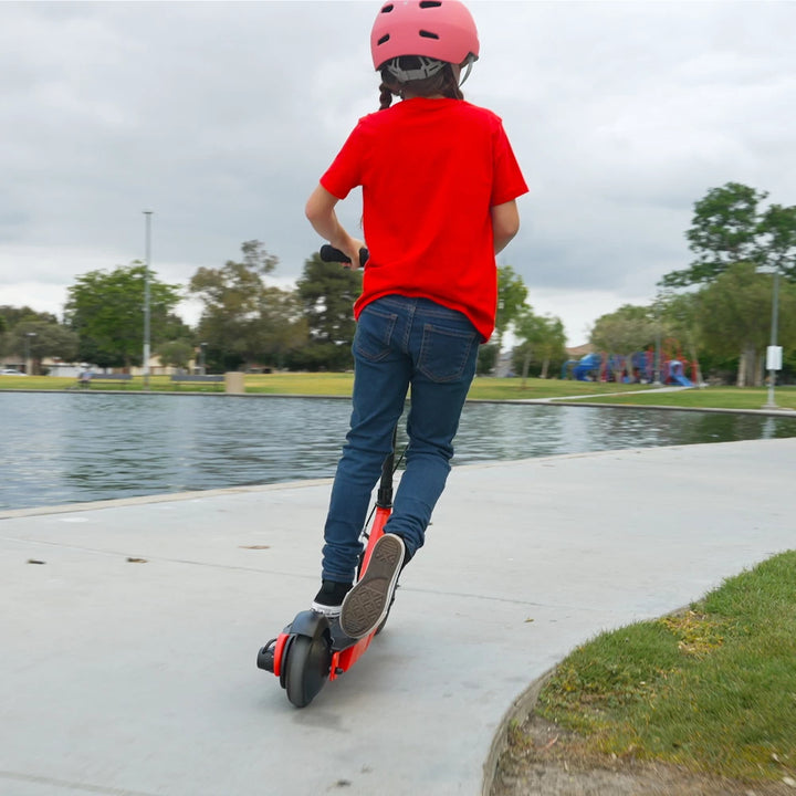 Rear view of a child riding the Razor PowerCore Launch electric scooter by a lake, ideal for children aged 8+ years, promoting safe outdoor fun.