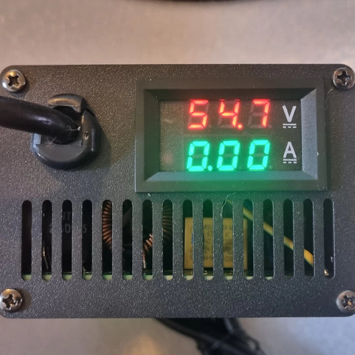 Close-up of the LED display on EMOVE Roadrunner Supercharger, showing voltage (54.7V) and adjustable amp output.