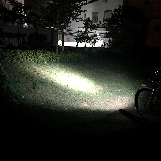 Night-time outdoor demo of the TRLIFE USB Rechargeable LED Bike Light, casting a powerful beam across a grassy area for superior visibility.