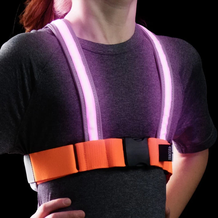 Front view of a child wearing the TracerJR LED Safety Vest with bright pink LED lights glowing in low light.