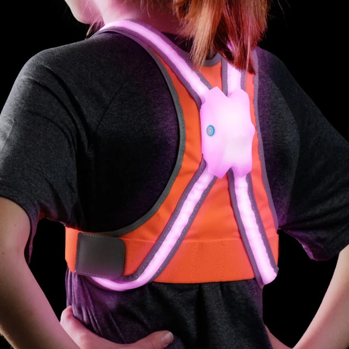 Rear view of a child wearing the TracerJR LED Safety Vest with pink LED lights, highlighting the glowing back panel and reflective strips.