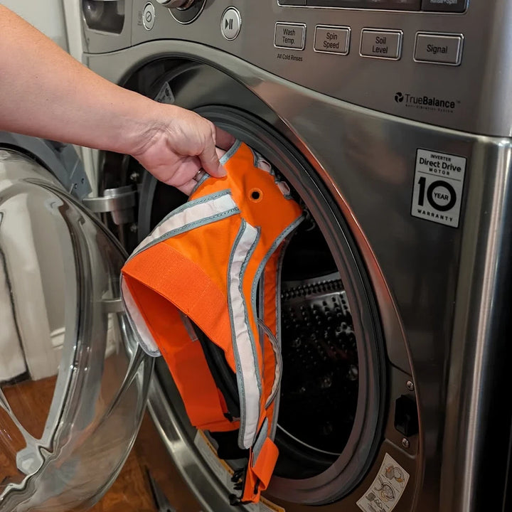 The TracerJR LED Safety Vest being placed in a washing machine, showing its machine-washable design.